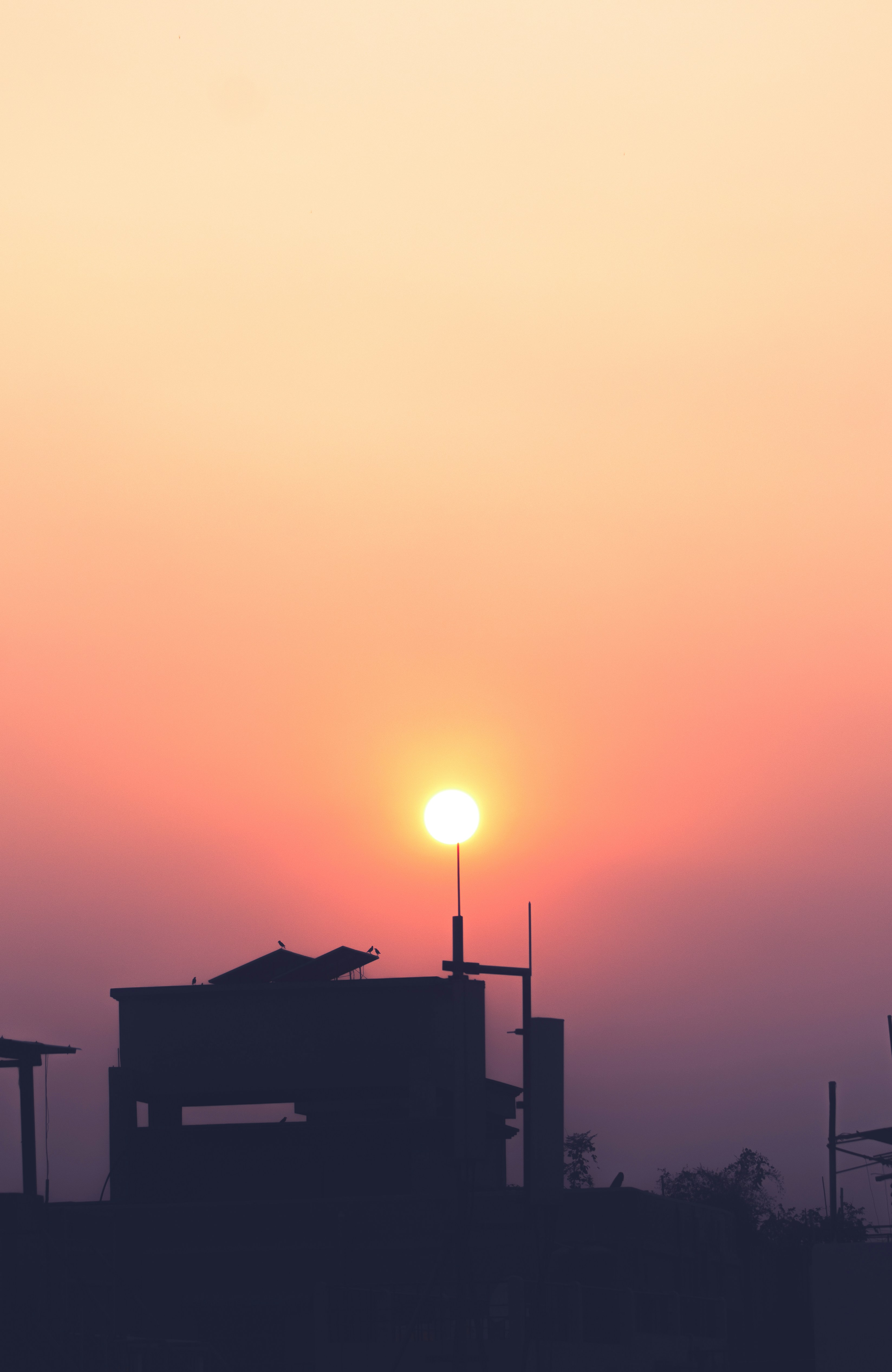 the sun is setting behind a building with a clock tower