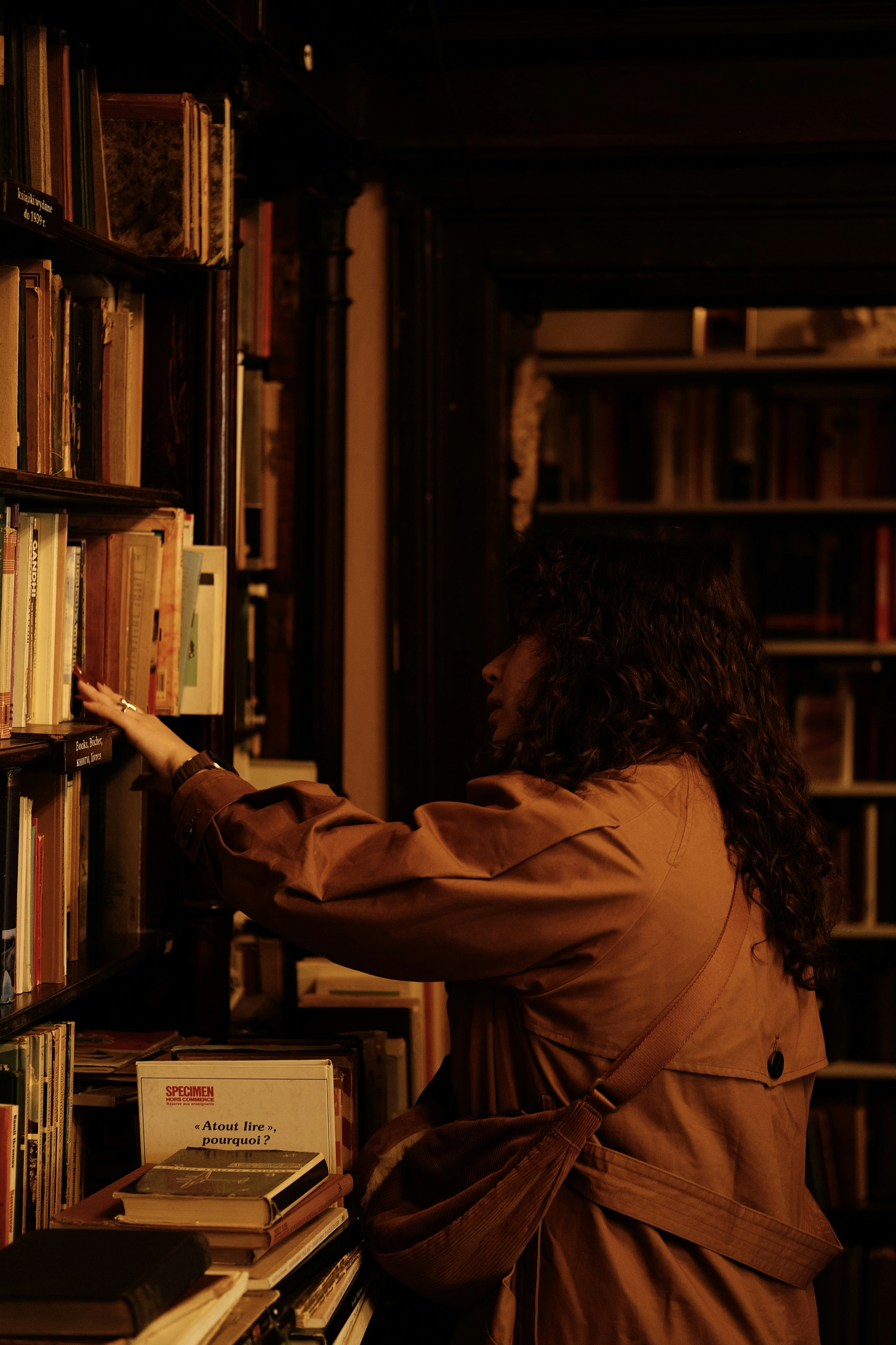 eine Frau, die in einer Bibliothek nach einem Buch greift