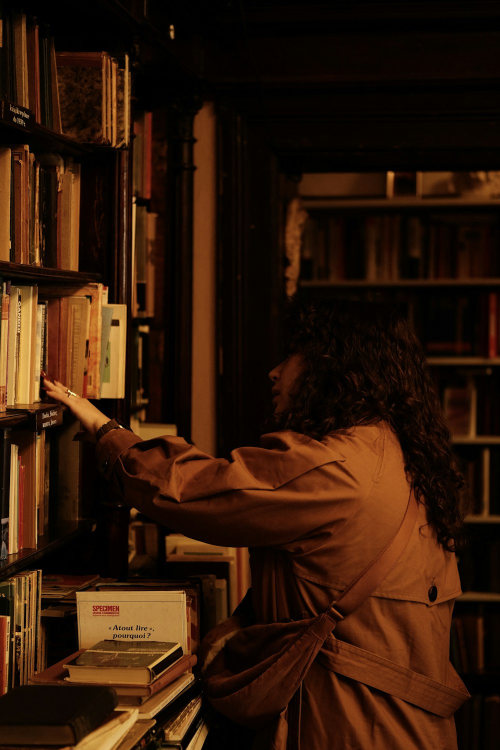 uma mulher pegando um livro em uma biblioteca