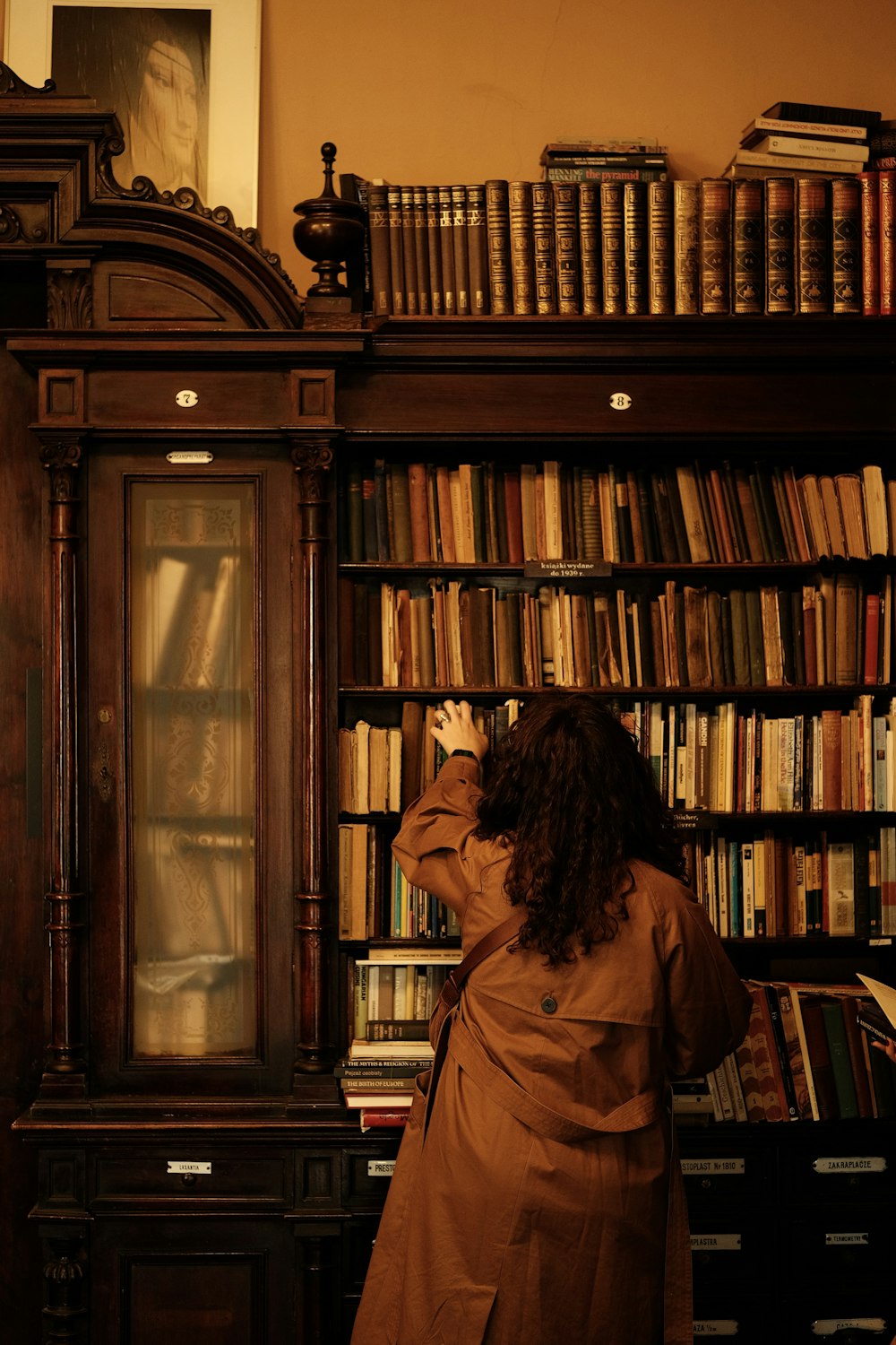 une femme debout devant une étagère de livres
