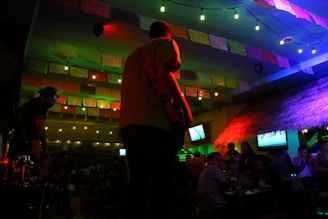 a man standing in front of a tv in a room filled with people
