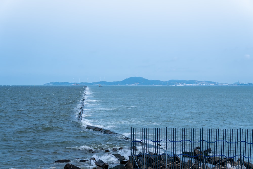 a view of a body of water with a fence in the foreground