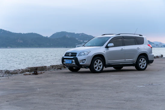 A sleek Toyota Sienna parked curbside with city landmarks of San Francisco in the background during golden hour.