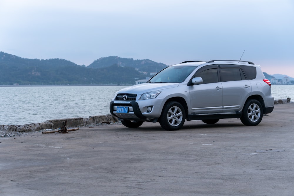 a silver suv parked on the shore of a lake