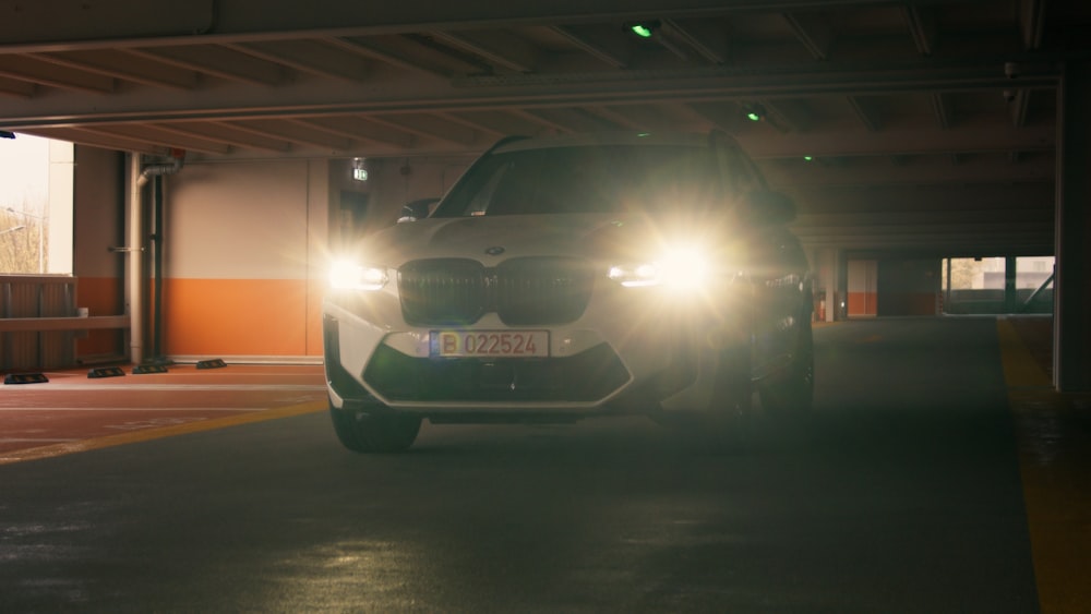 a white car driving through a parking garage