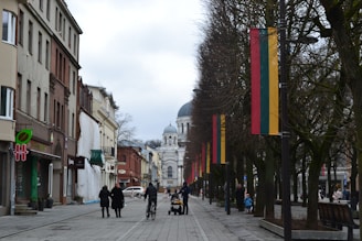 a group of people walking down a street next to tall buildings