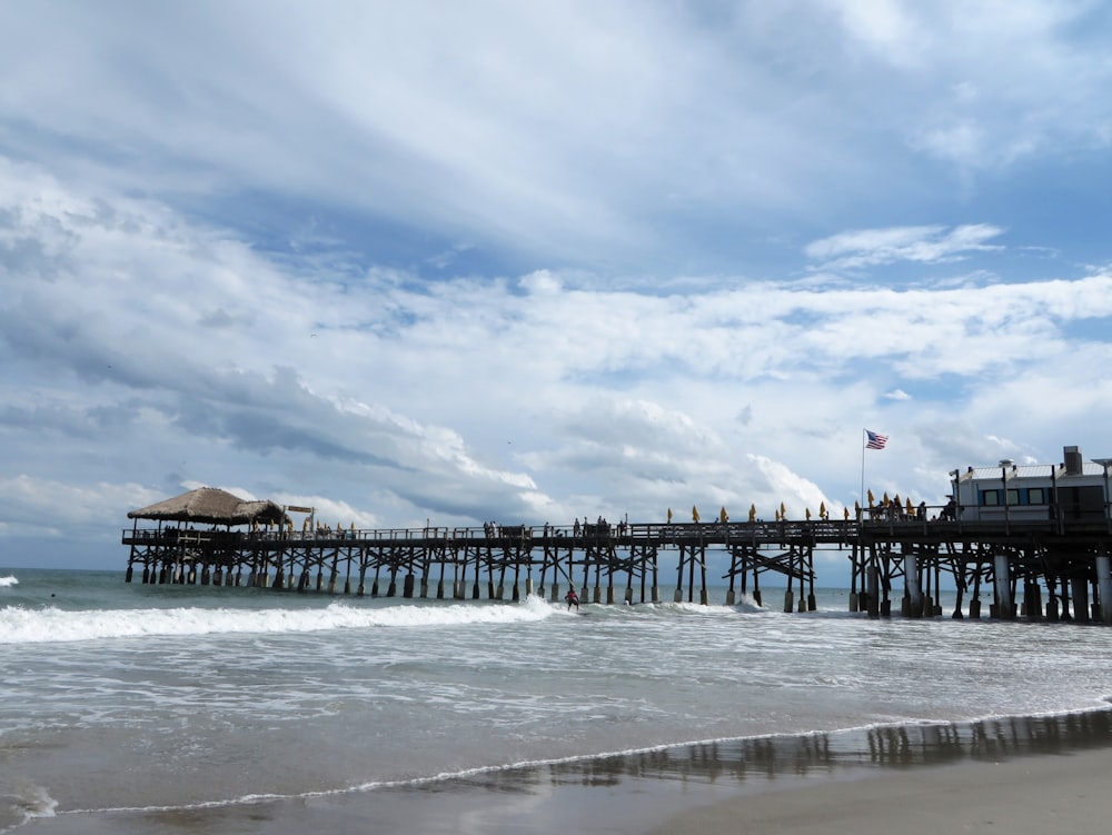 a pier on the beach with people standing on it