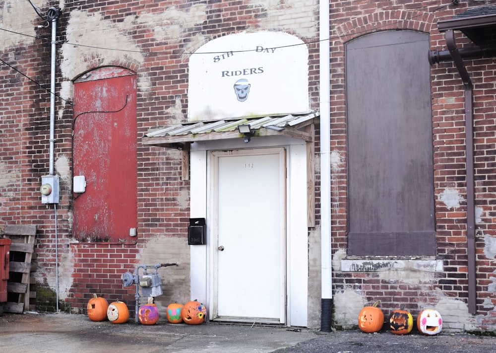 a brick building with a white door and some pumpkins
