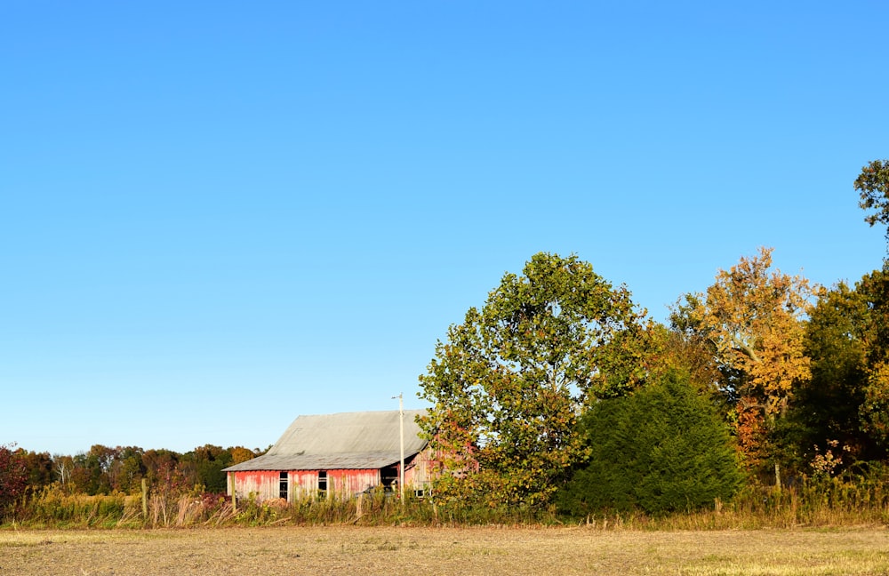 an old barn in a field with trees in the background