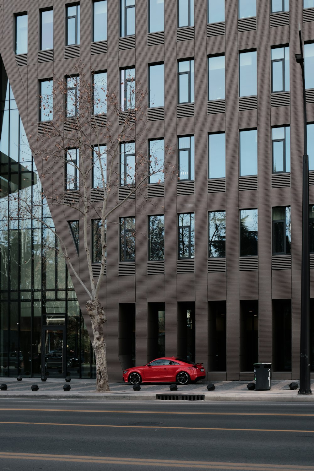 a red car parked in front of a tall building