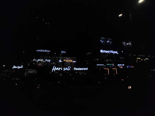 A vibrant LED sign board glowing brightly outside a local shop in Naroda at dusk.
