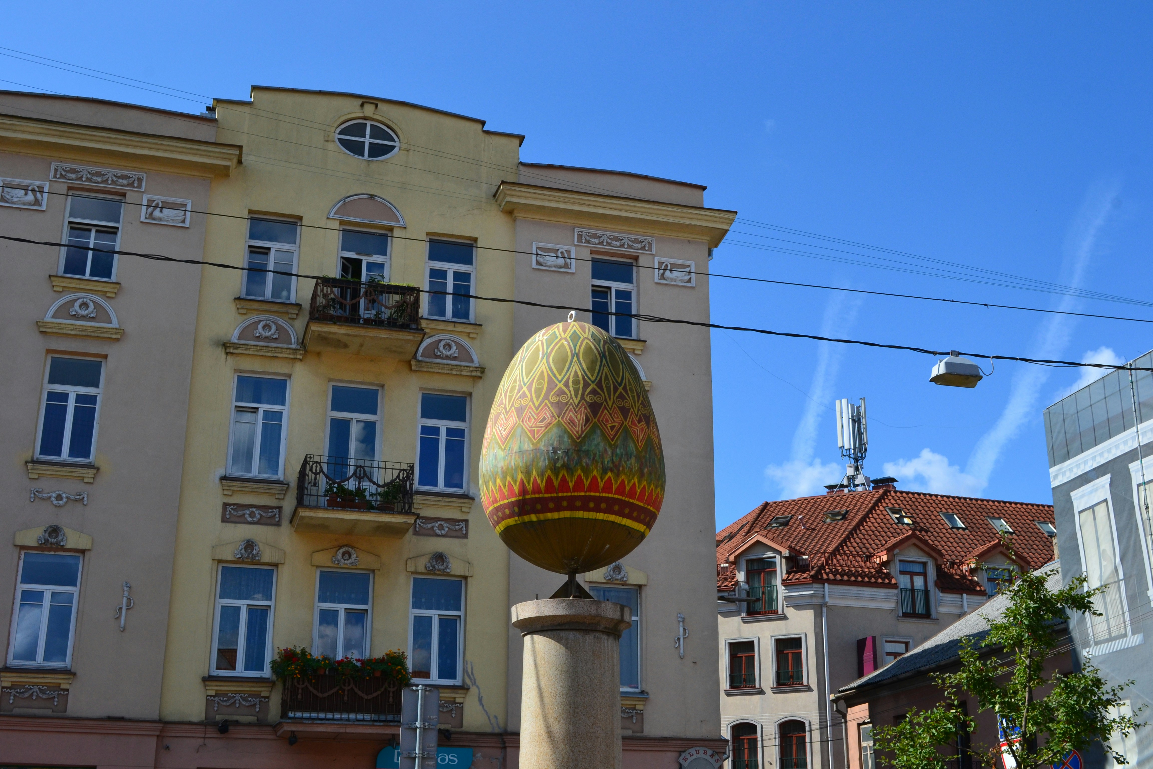 a large egg sitting on top of a statue in front of a tall building