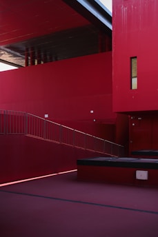 A minimalist architectural sketch with bold red accents highlighting structural details.