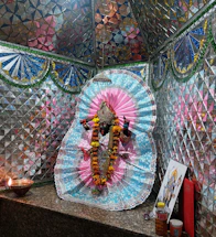 An intricate traditional Indian havan kund glowing warmly amidst sacred puja items and maroon-gold temple patterns