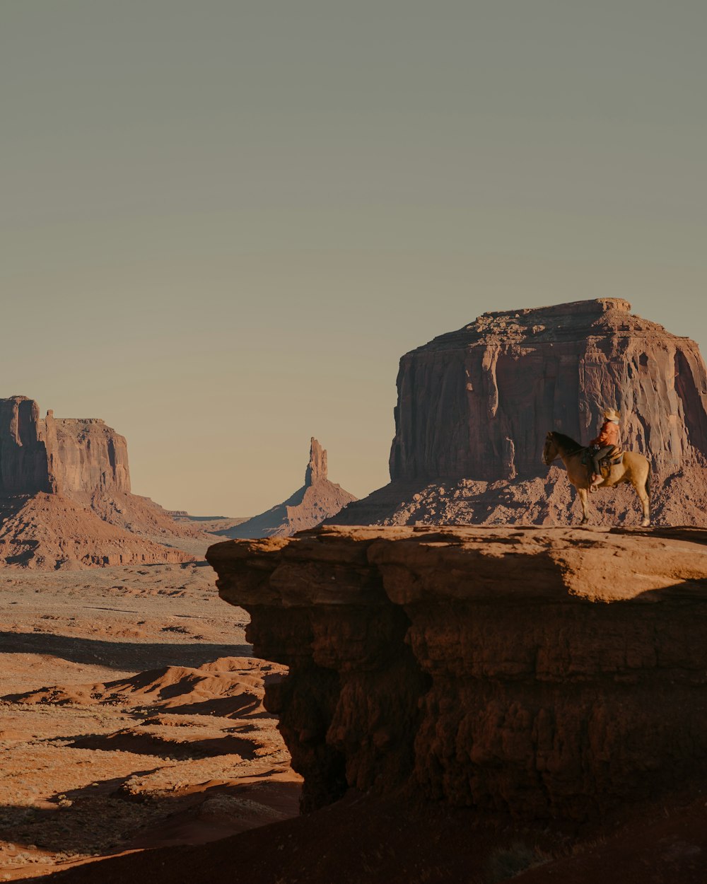 a man riding a horse on top of a cliff