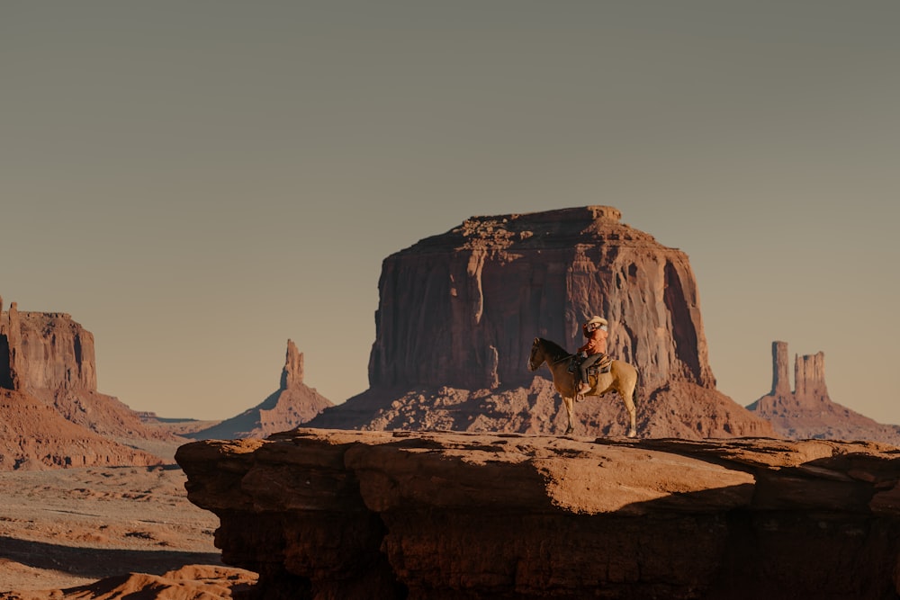 a man riding a horse across a desert landscape