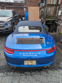 A red Porsche Cayman parked near a historic castle in Edinburgh with autumn leaves scattered around