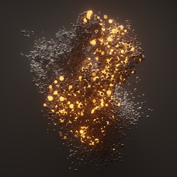 A cluster of small, glowing spheres creates a dynamic, swirling pattern. The spheres emit a warm, golden light against a dark background, giving an impression of energy and movement. The light gradually diffuses through the image, creating a captivating contrast with the surrounding darkness.