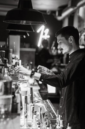 An elegant bartender crafting a signature cocktail under soft, moody lighting.