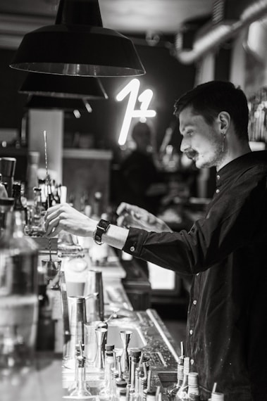 A sleek, modern bar setup with a bartender expertly mixing a cocktail under moody lighting.