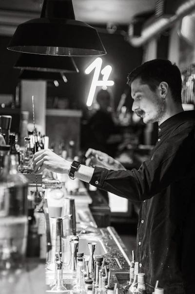 Bartender mixing a signature cocktail behind the dimly lit bar at Secret Story.