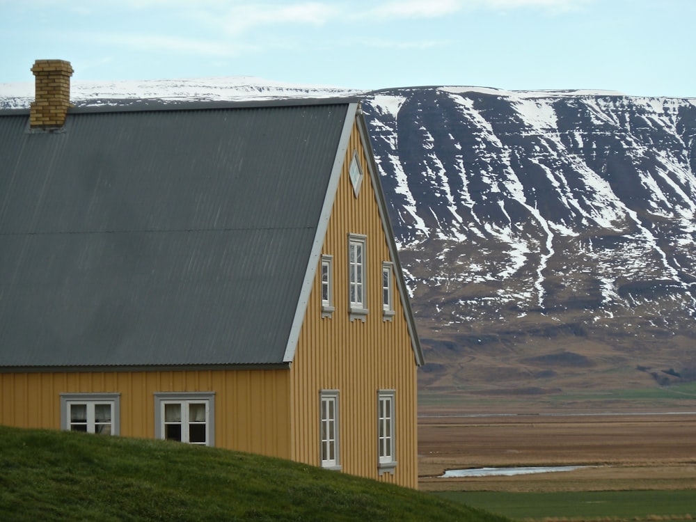 a yellow house with a mountain in the background