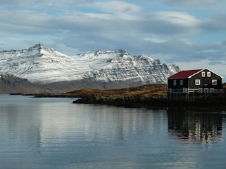 greeenland house on the shore of a lake with mountains in the background