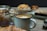 A mug of cappuccino with latte art is surrounded by an assortment of pastries including a croissant, muffins, and brownies. The setting appears cozy, with the pastries and coffee arranged on a wooden surface.