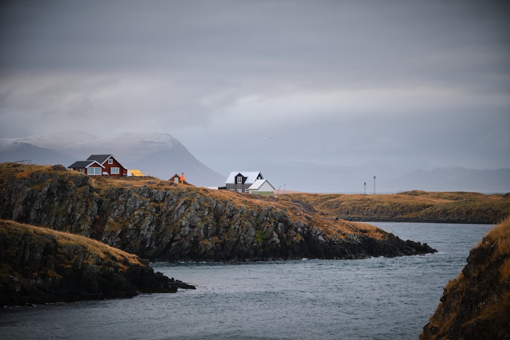 a couple of houses sitting on top of a hill next to a body of water