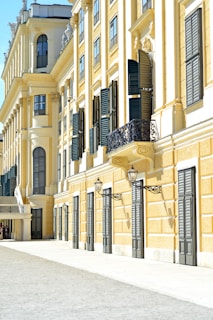 a yellow building with black shutters and a balcony