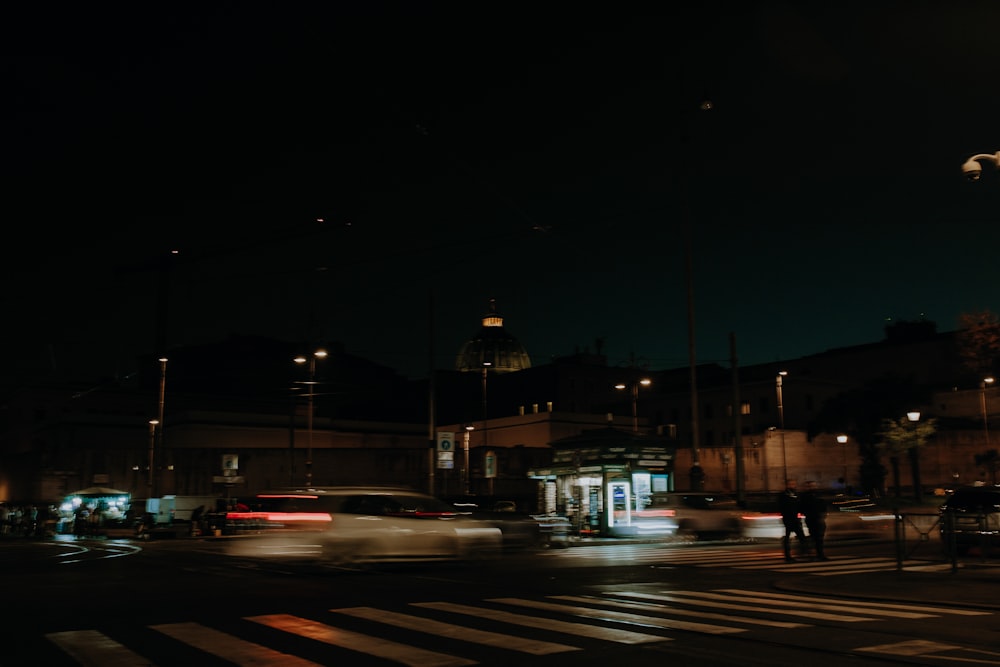 a city street at night with cars driving by