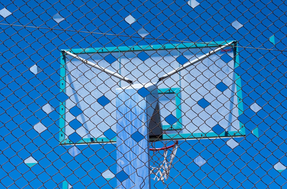 a basketball hoop is seen through a chain link fence