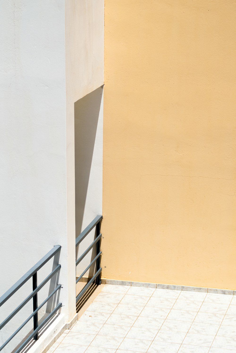 a white building with a black railing and a yellow wall