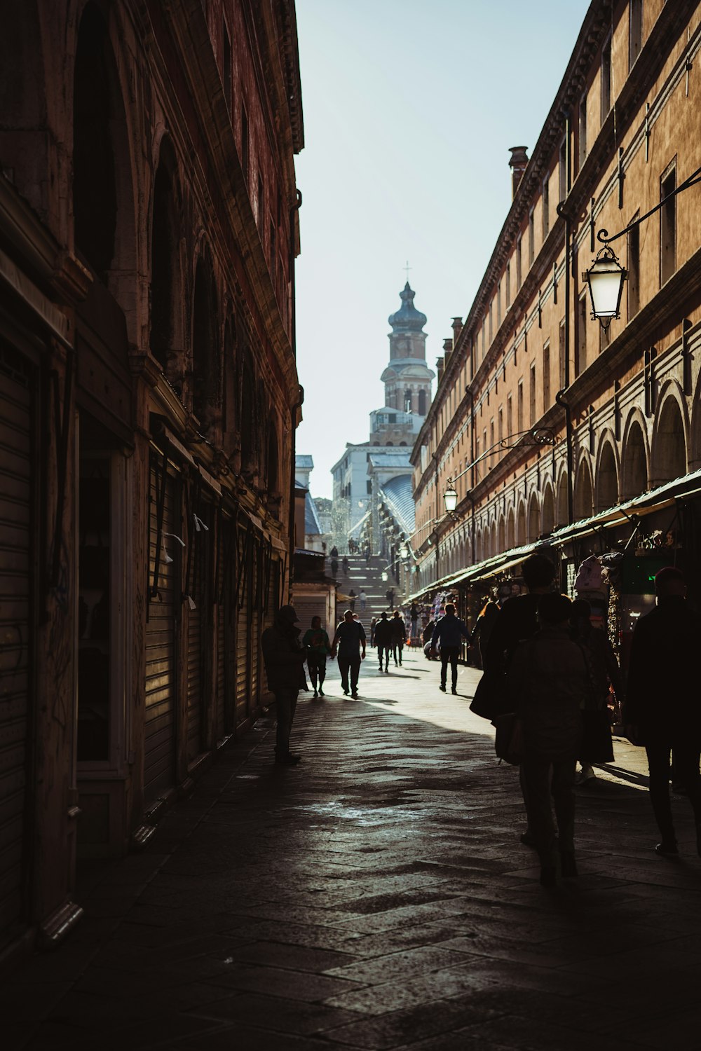 a group of people walking down a street next to tall buildings