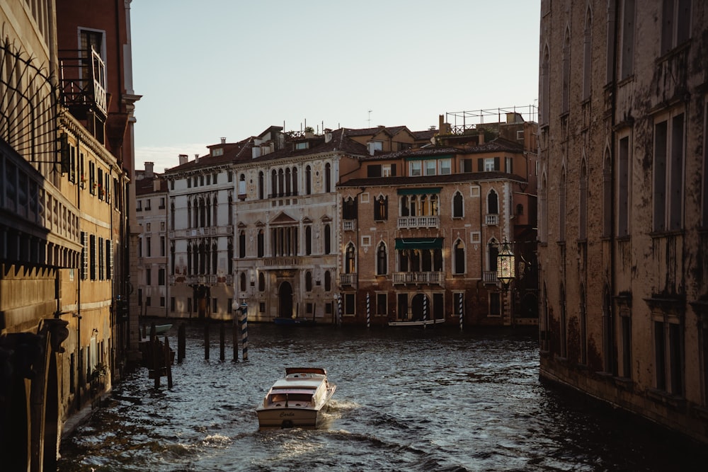 a boat traveling down a river next to tall buildings