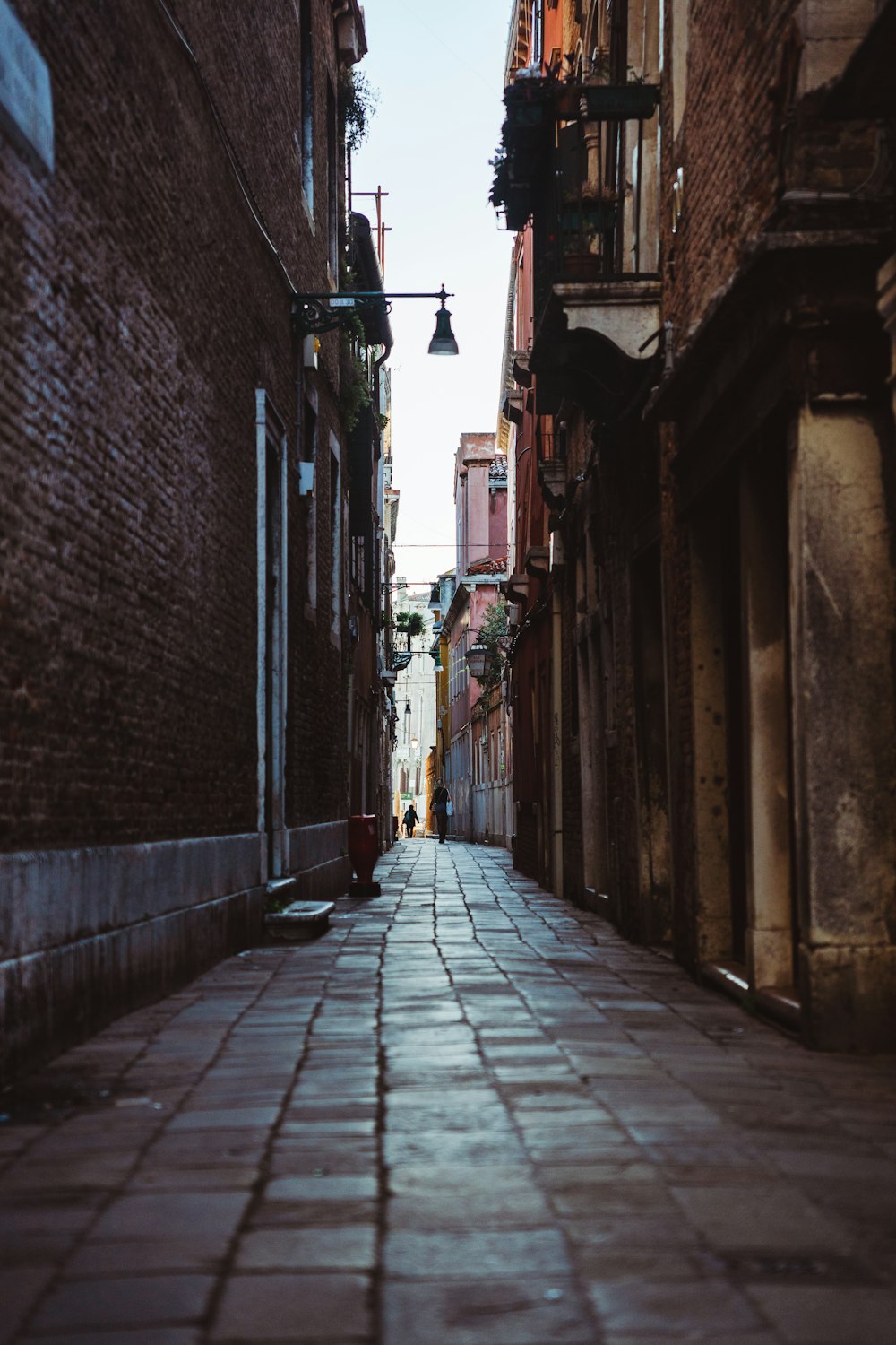 a narrow alley way with a lamp hanging from the ceiling