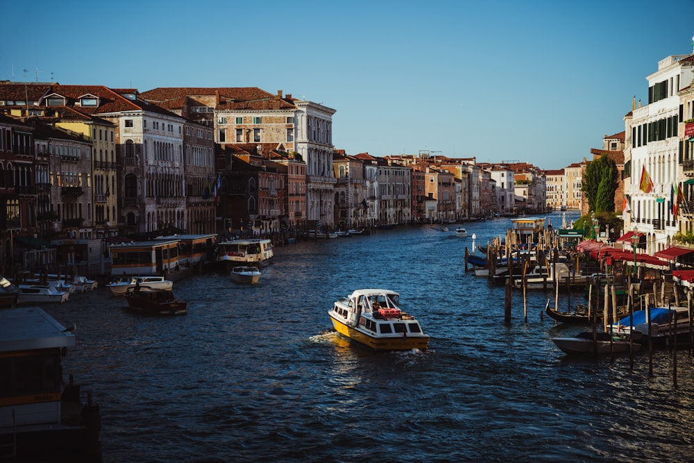 a boat traveling down a river next to tall buildings