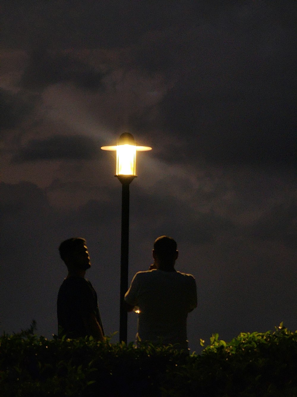 a couple of men standing next to each other under a street light