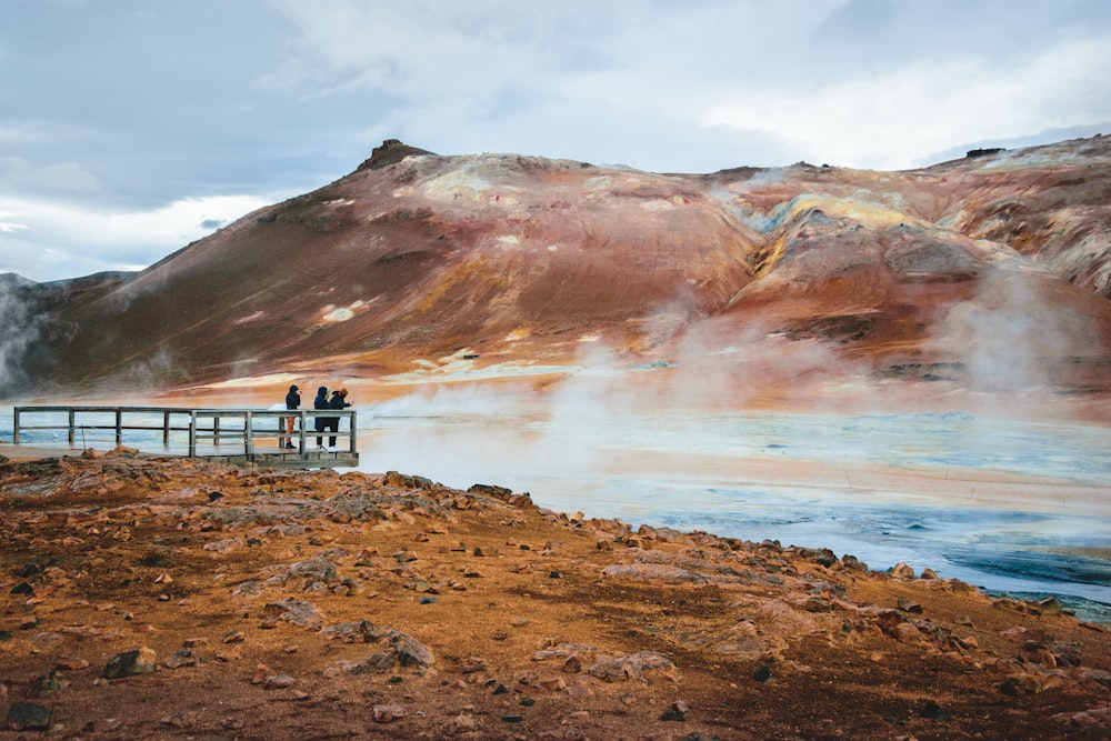 a couple of people standing on a bridge over a body of water