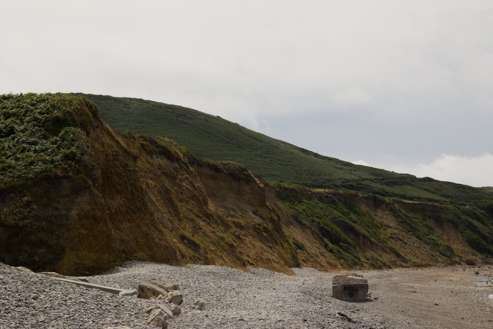 a rocky beach with a hill in the background