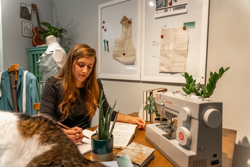 a woman sitting at a desk with a sewing machine