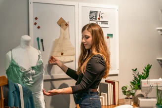 a woman standing in front of a dress on a mannequin