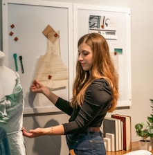 a woman standing in front of a dress on a mannequin