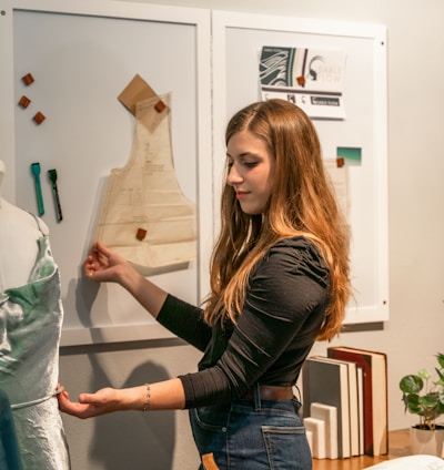 a woman standing in front of a dress on a mannequin