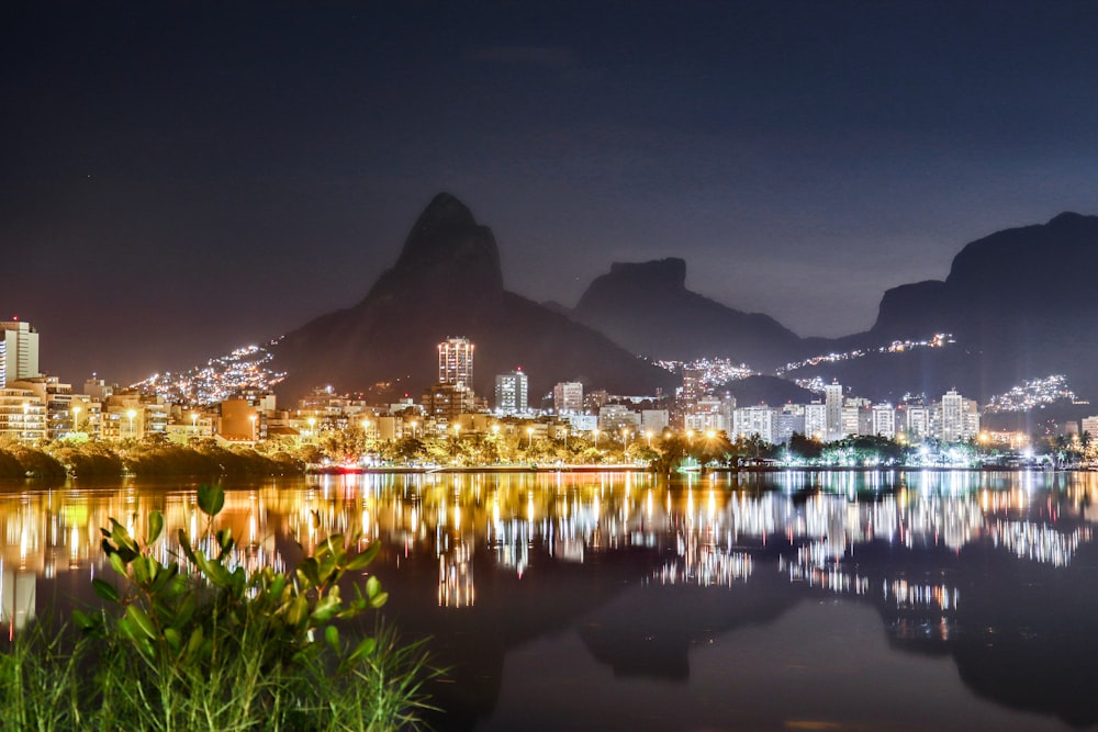 a city is lit up at night with mountains in the background