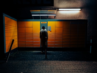 A friendly staff member packing a brightly colored DHL box behind a service counter.