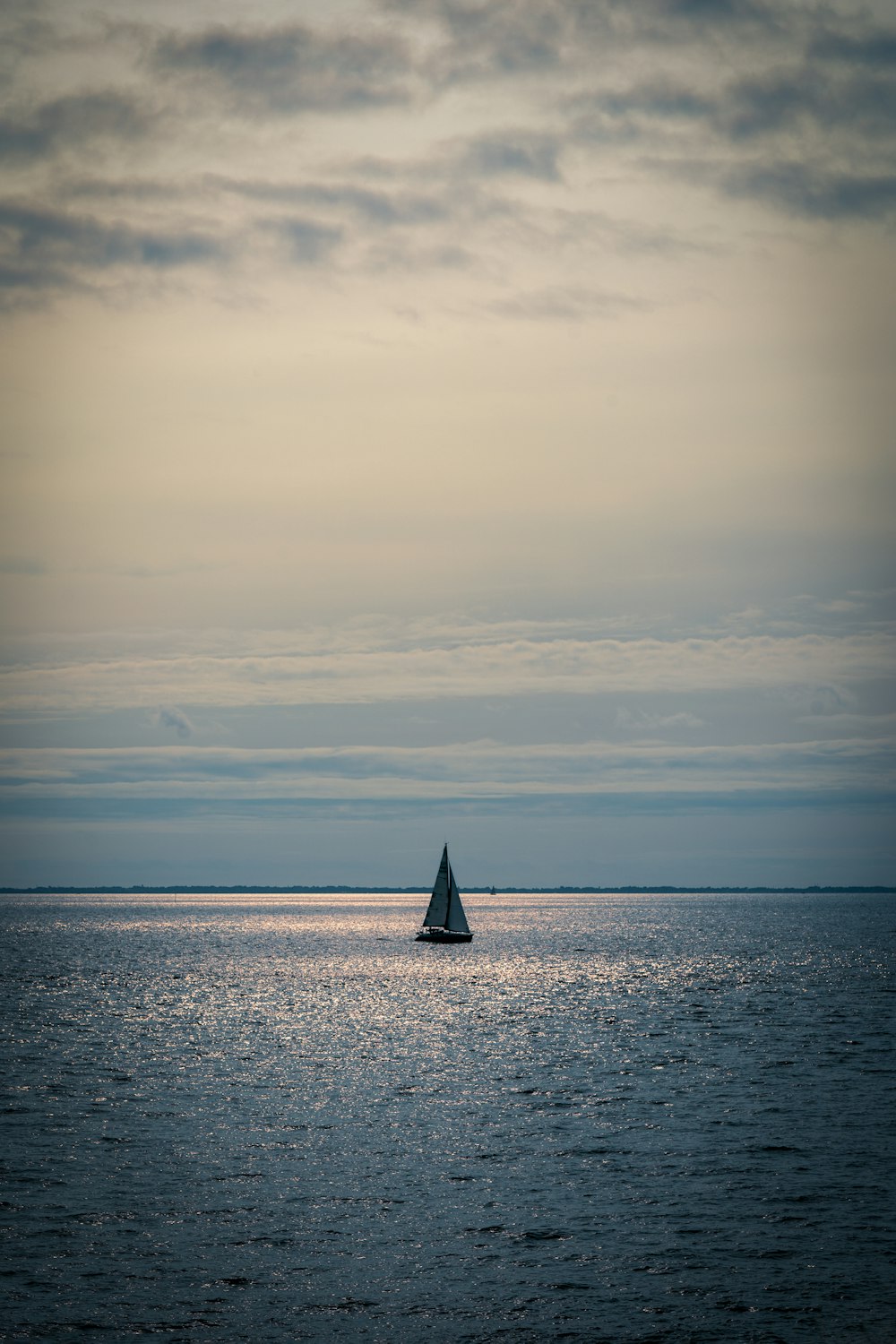 a lone sailboat in the middle of the ocean