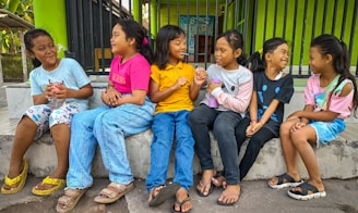 a group of young children sitting on a cement bench