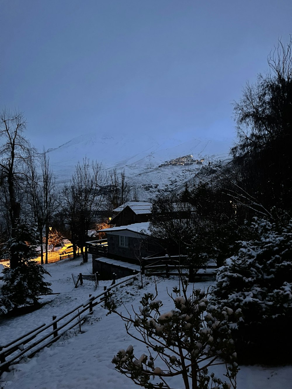 a snow covered yard with a fence and trees