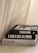Three stacked fashion books with large, bold titles are placed near a soft, flowing curtain. The books feature grayscale covers with a modern, minimalist design.